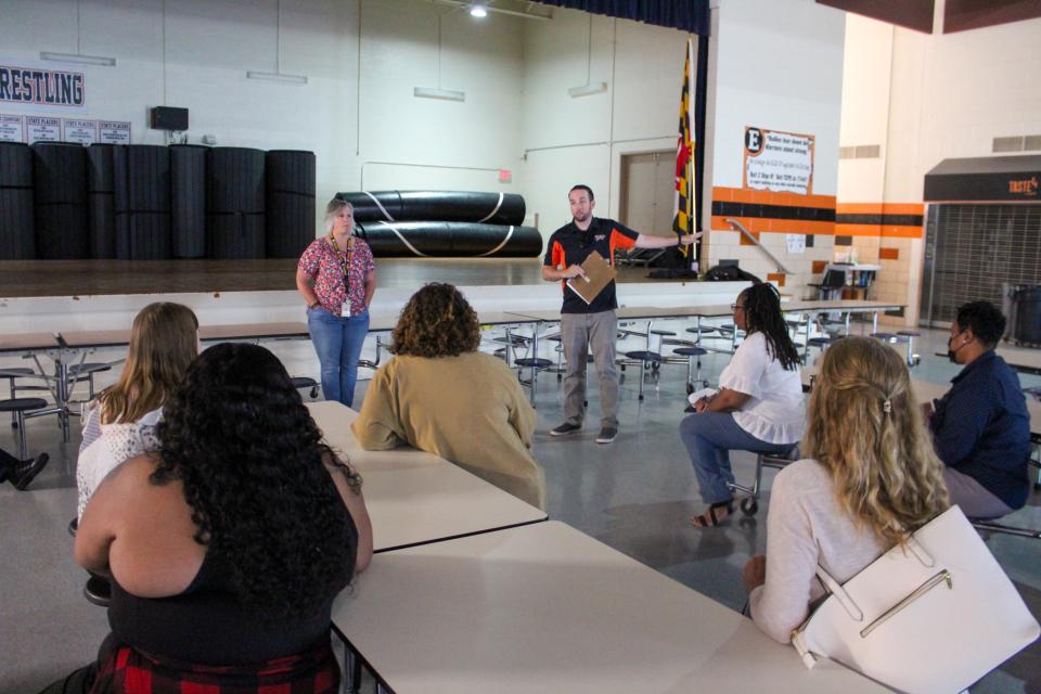 Ben Pittsley points out where food is distributed. The cafeteria area is used for food distribution and a gathering space. The gym is preserved as the designated sleeping area.