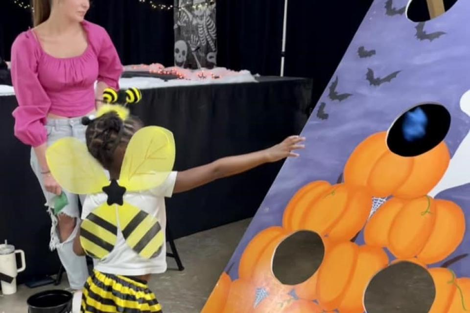 Bumblebee tosses bean bags at Halloween themed bag toss game.